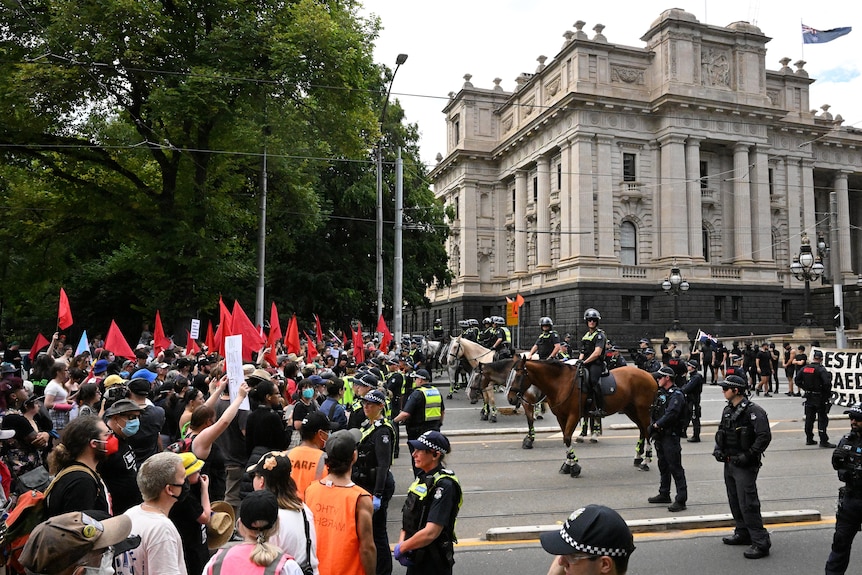 A line of police separates a counter-rally from an anti-trans rally outside Victoria's Parliament House.