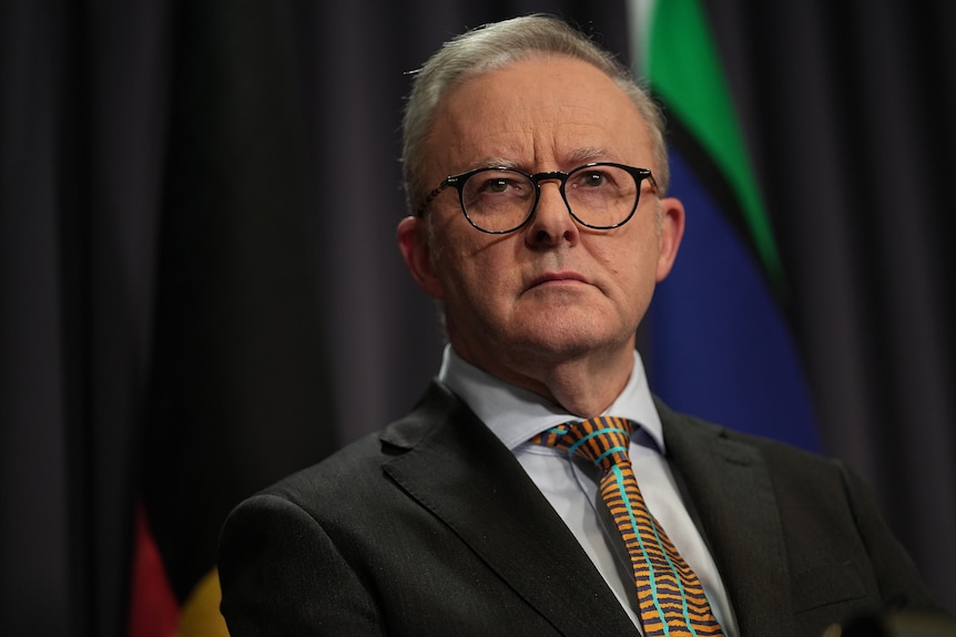 Anthony Albanese, wearing a suit and glasses, looking serious.