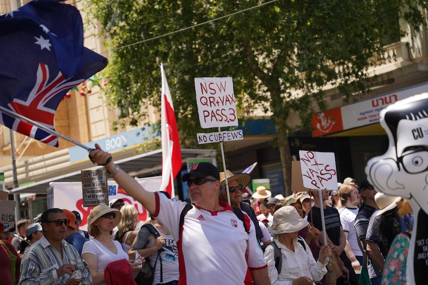 A person waving an Australian flag at a protest.