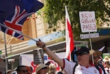 A person waving an Australian flag at a protest.