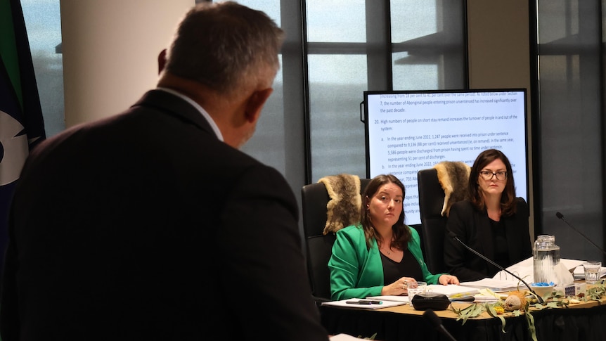 Two women in a meeting room being questioned by a man