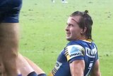 A footballer sitting down winks to a teammate