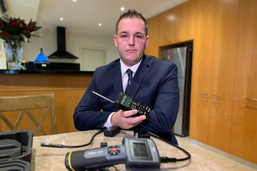 Nicholas Shaw looks at the camera, holding police equipment.