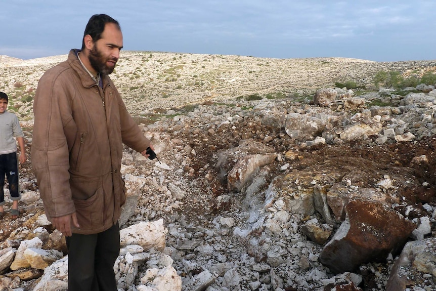 Escalating violence - a Syrian man points at a crater where a Scud missile hit in the town of Nasiriyeh.