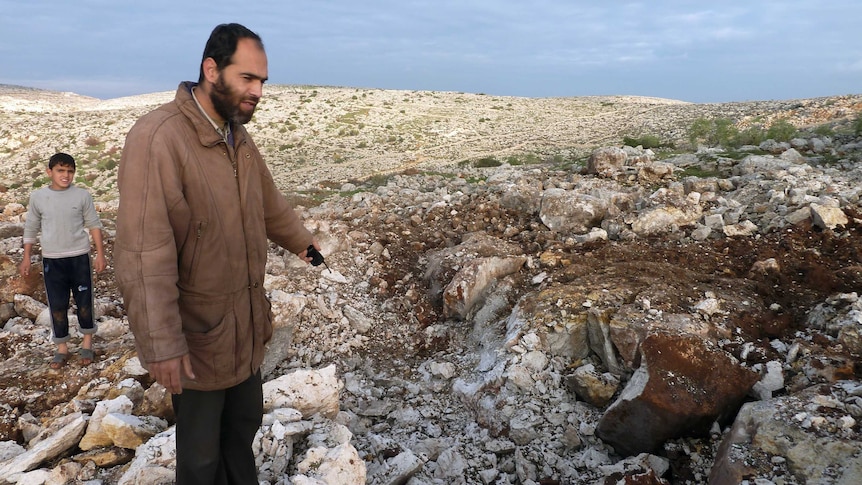 Escalating violence - a Syrian man points at a crater where a Scud missile hit in the town of Nasiriyeh.