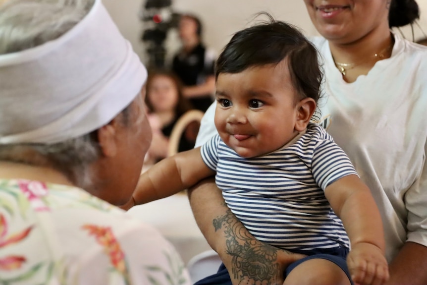 Indigenous baby being blessed by an old woman with white bandage around her head