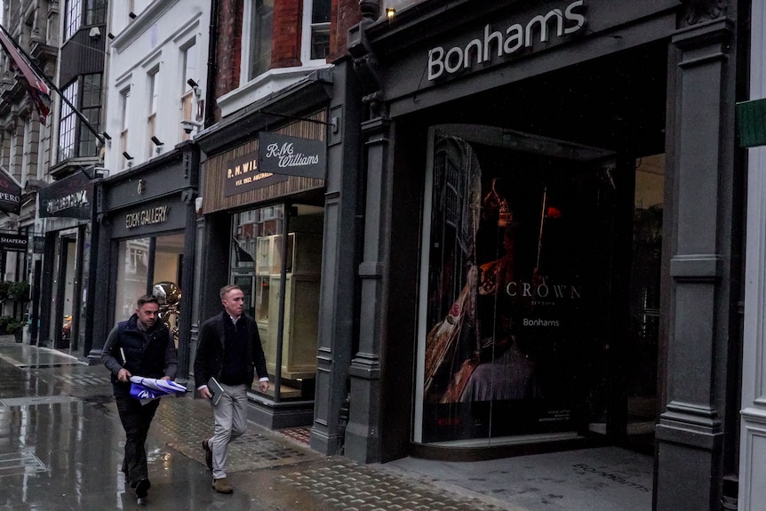 Two men walk past the London office of auction house Bonham's.