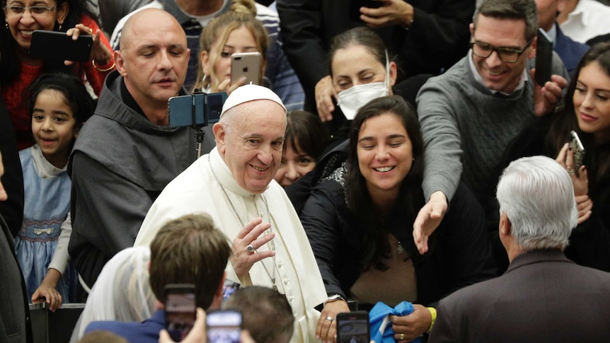 Pope Francis arrives for his weekly general audience at the Vatican surrounded by worshippers.