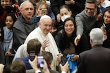 Pope Francis arrives for his weekly general audience at the Vatican surrounded by worshippers.