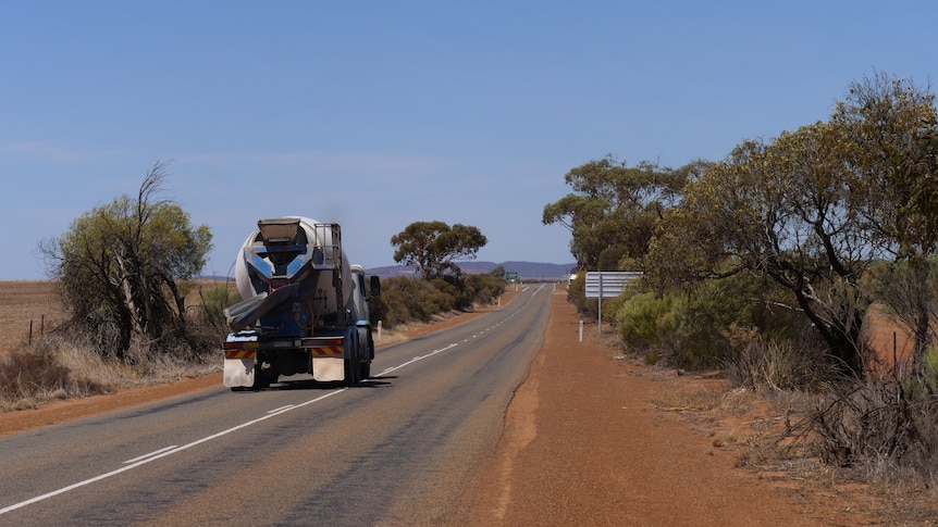 A large truckl travels on a country road. 