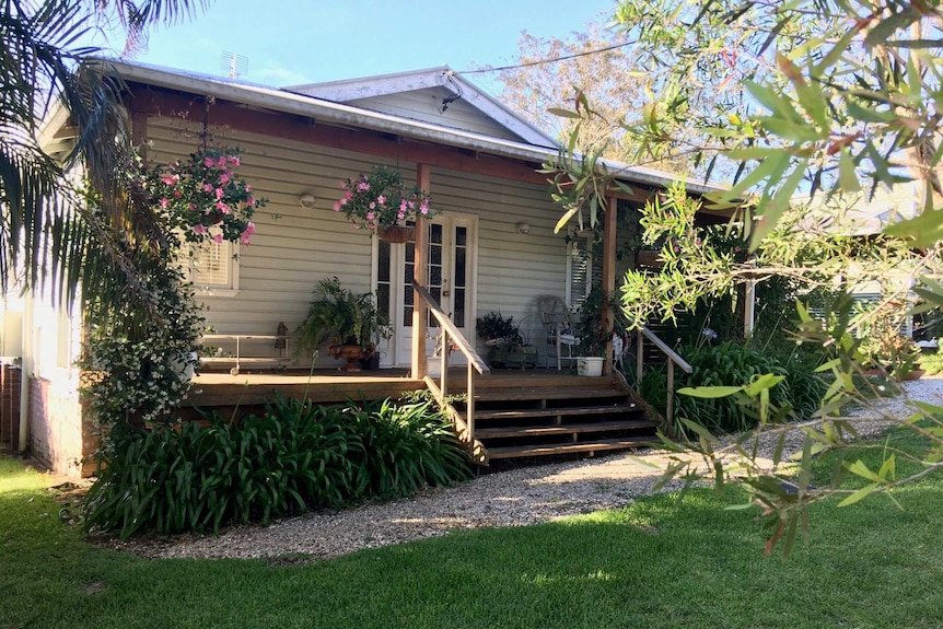 A weatherboard cottage and verandah covered with flowers
