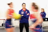 Michelle Cowan folds her arms while in the changeroom as players wizz past in a blur.
