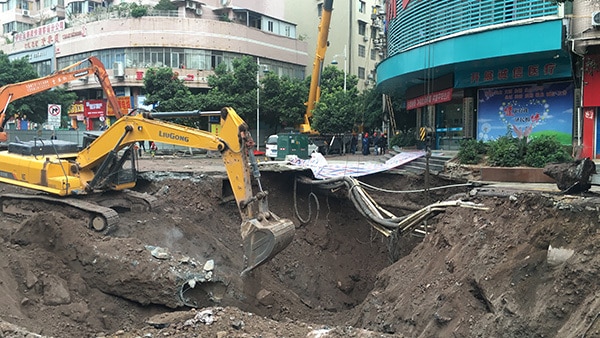 A yellow crane digs in a deep sinkhole in China.
