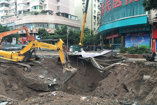 A yellow crane digs in a deep sinkhole in China.