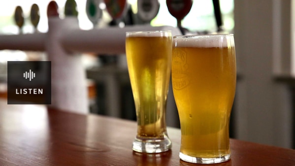 Two glasses of beer sitting on a pub counter. Has Audio.