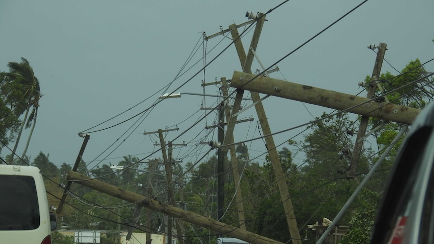 Electricity poles have fallen along a street with all the wires tangled up.