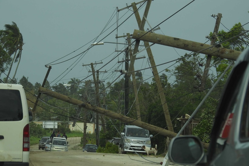 Electricity poles have fallen along a street with all the wires tangled up.