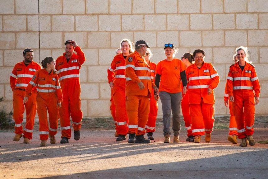 About 10 Carnarvon SES Volunteers walk towards the camera in their orange uniforms. 