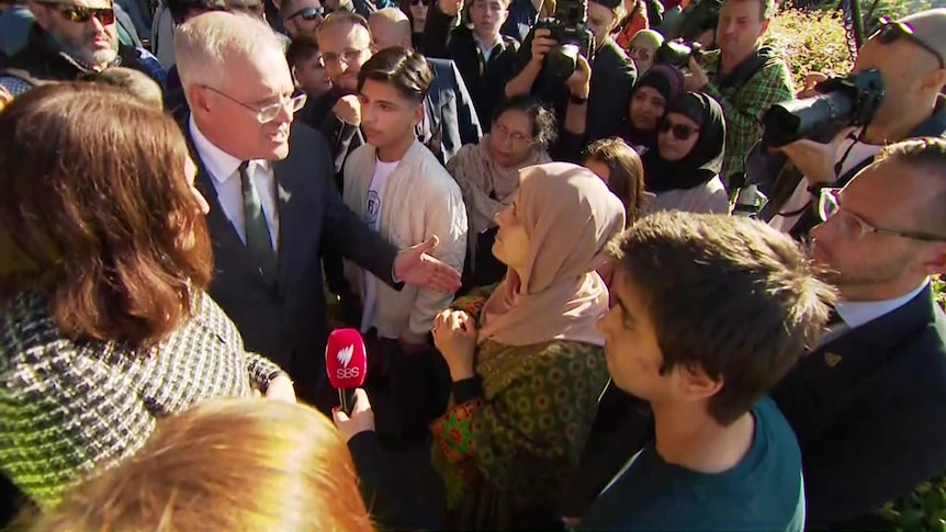Scott Morrison is surrounded by a tightly packed crowd as he addresses a woman in a hijab.