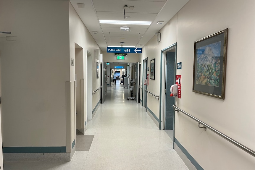 Hospital corridor people far up other end walls are white with grey doors 
