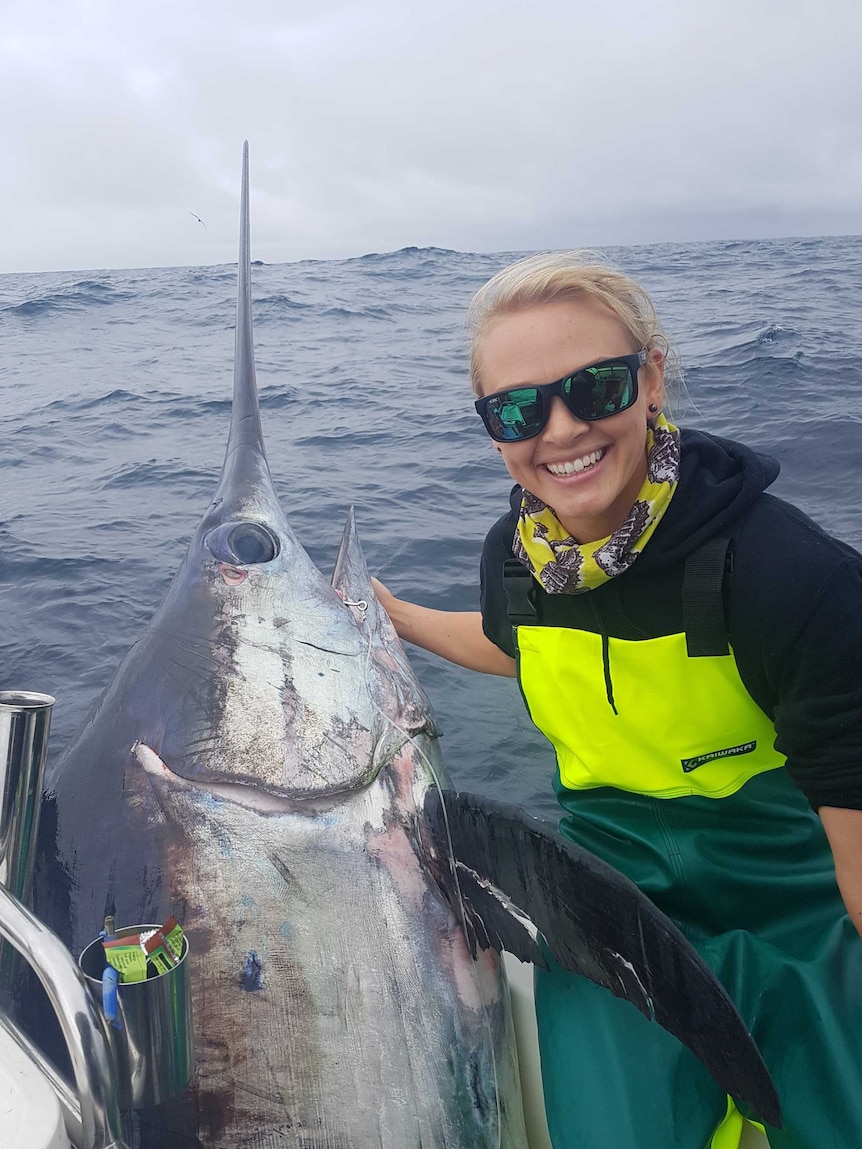 Naomi Wisby on a boat with a large swordfish.