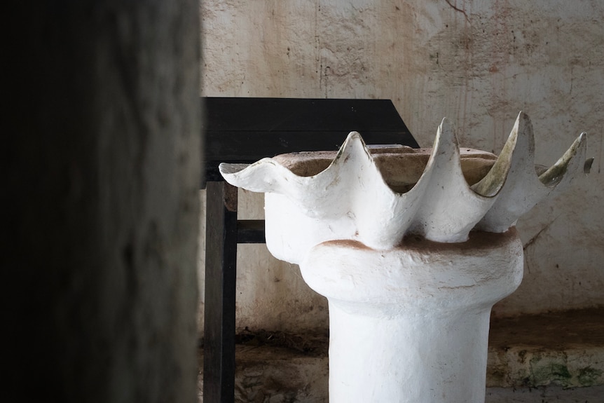 Interior shot of the decaying stone church with a baptismal font made from a giant clam shell