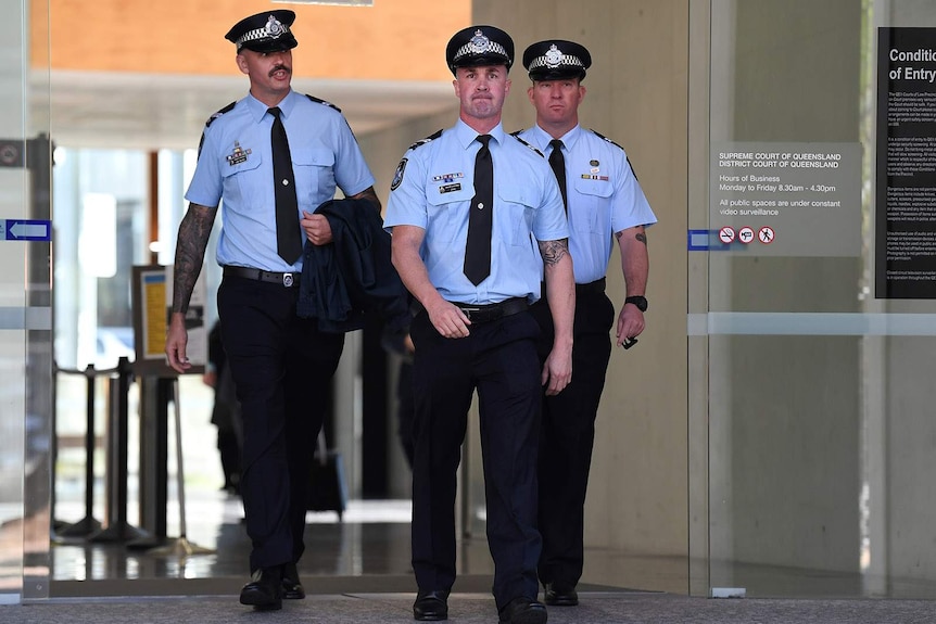 Three uniformed policemen walk from the Brisbane District Court building