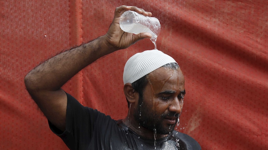 Man pours water on his head to cool off from the heat in Pakistan