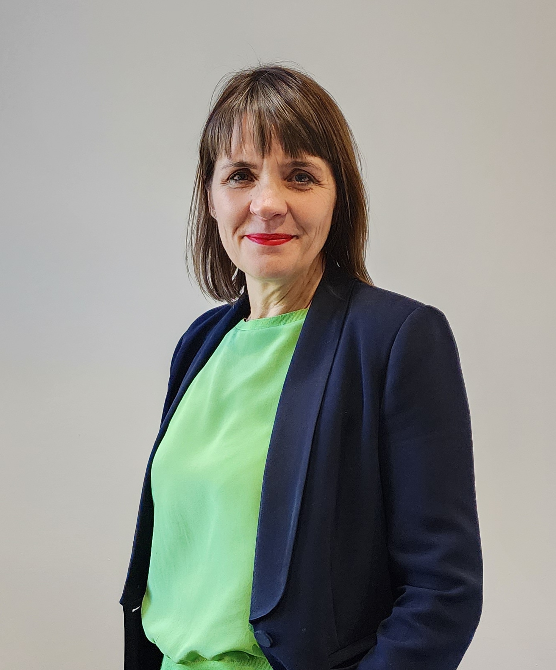 Uma mulher de cabelos escuros e uma jaqueta escura.