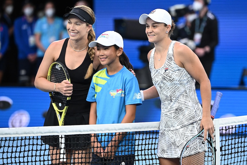 Ash Barty and Danielle Collins pose with a child at the net before the Australian Open final.