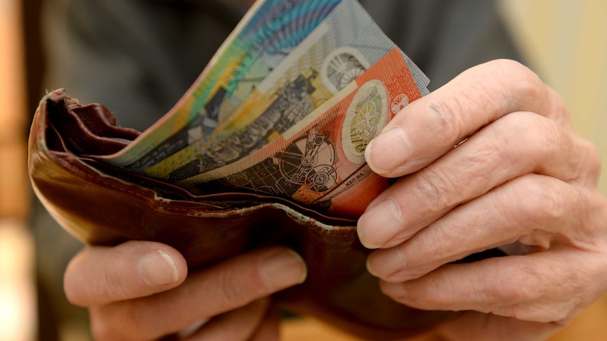 Hands hold onto Australian bank notes and a brown wallet.