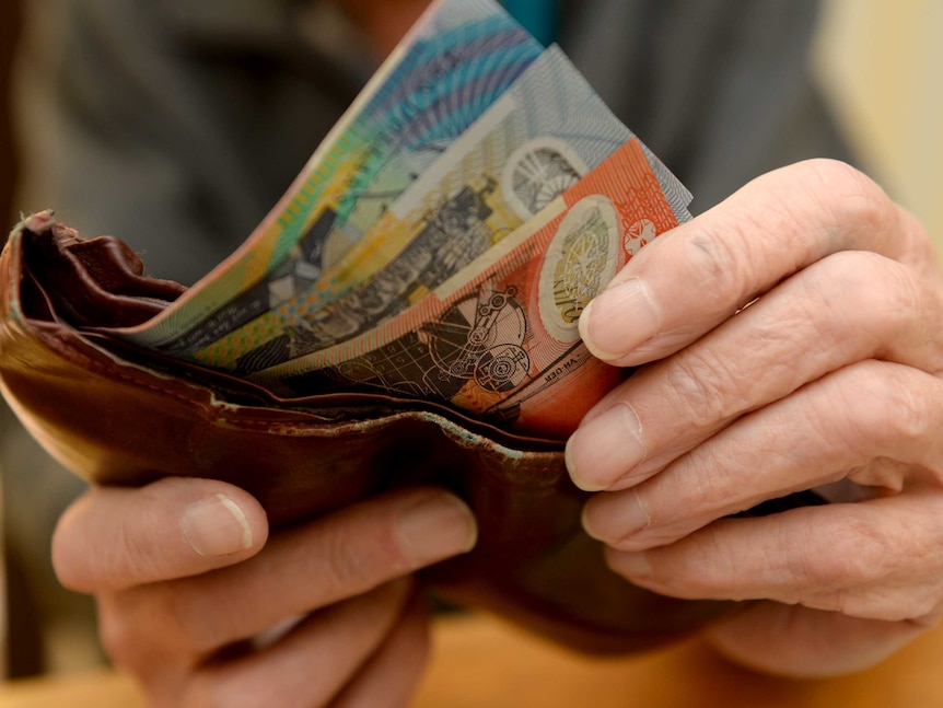 Hands take Australian money notes out of a wallet.