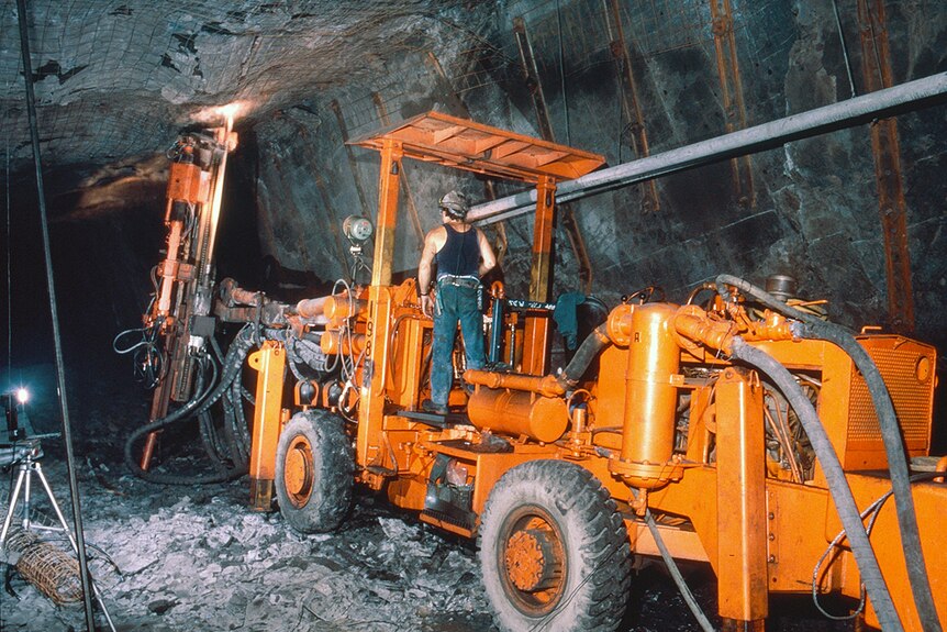 A miner operates a large truck underground.