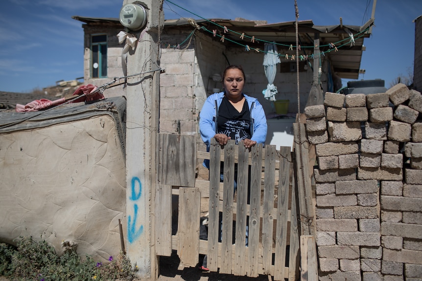 A woman stands behind a gate.