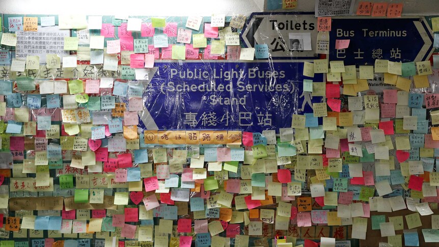A tunnel wall covered in colourful sticky notes with Cantonese writing on them