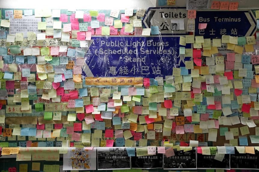 A tunnel wall covered in colourful sticky notes with Cantonese writing on them