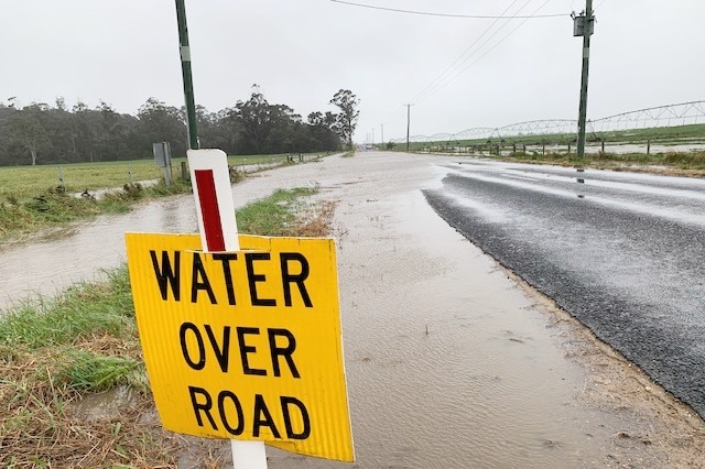 A sign warns of water over a road