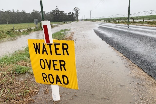 A sign warns of water over a road