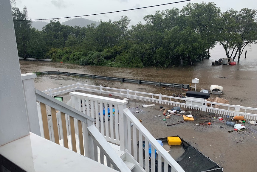 A view from a balcony shows water in the front yard high enough to flood downstairs.