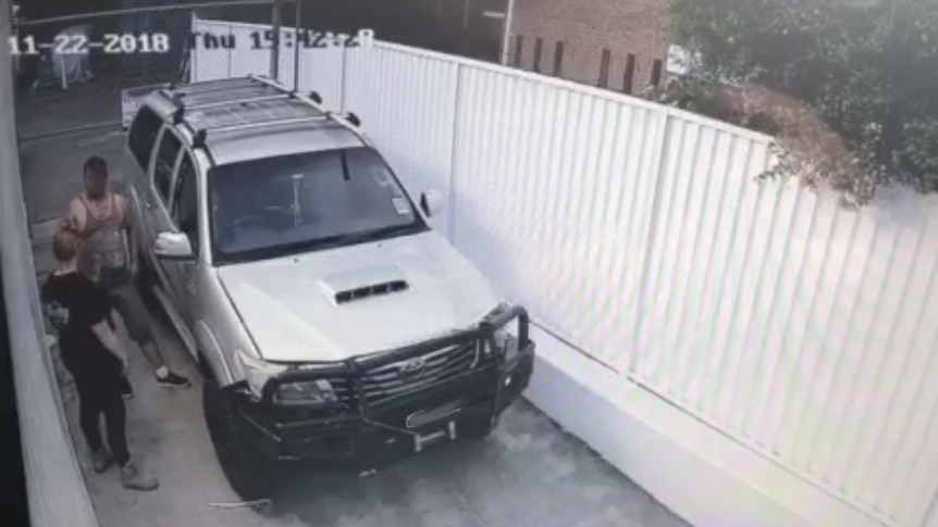 man talking to woman next to car in alleyway