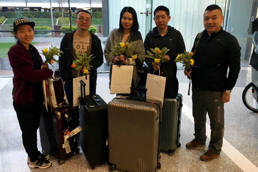 A group of travellers holding flowers.