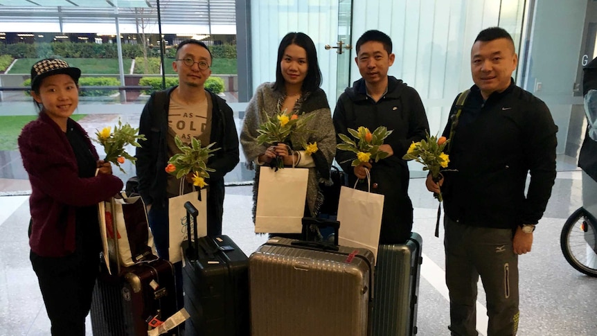 A group of travellers holding flowers.