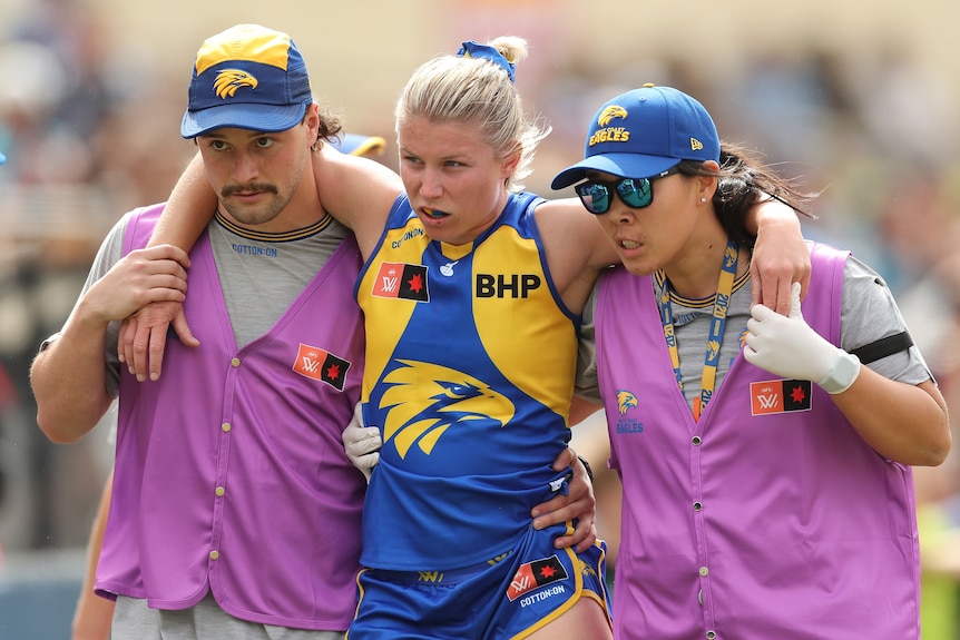 Kellie Gibson is helped from the field by two Eagles trainers after injuring her knee in round one, season seven