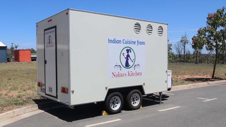 A parked food van with stumps underneath it