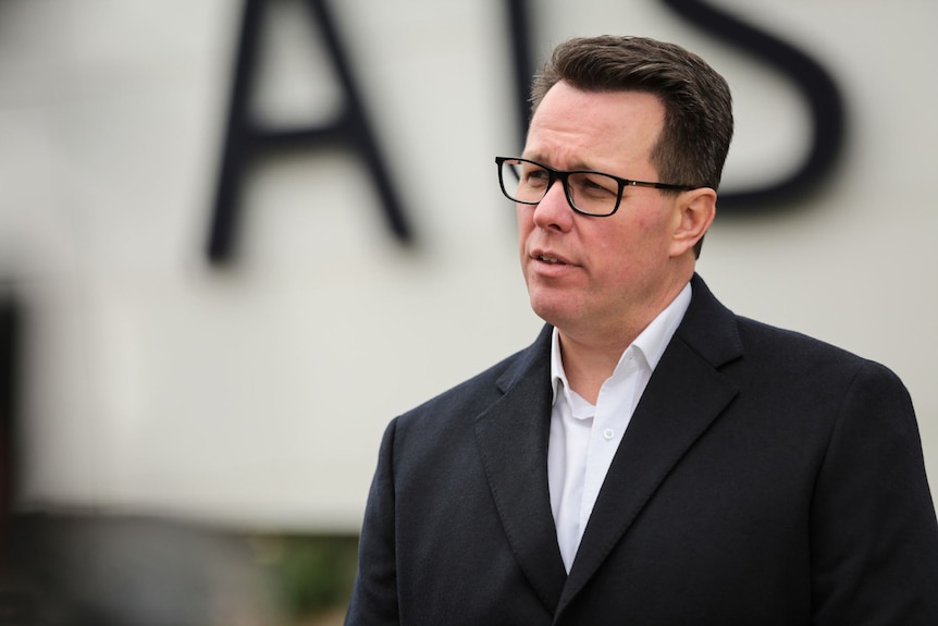 A man in a black suit jacket and glasses.