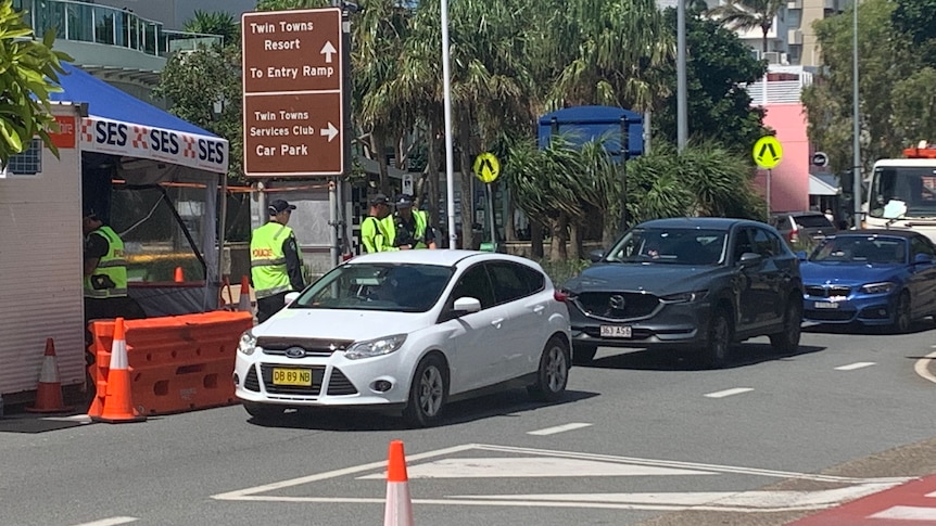 Police speak to people in a row of cars.