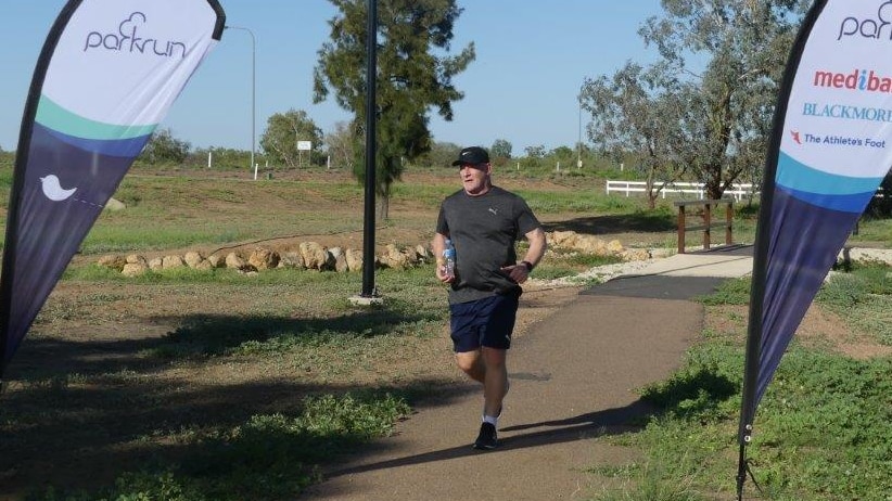 A man jogs towards the finish line of the Longreach Parkrun.
