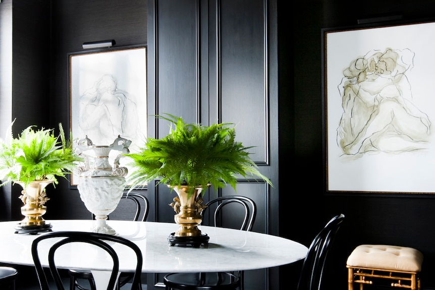 A styled dining room with black painted walls and ceiling trim and a dark carpet