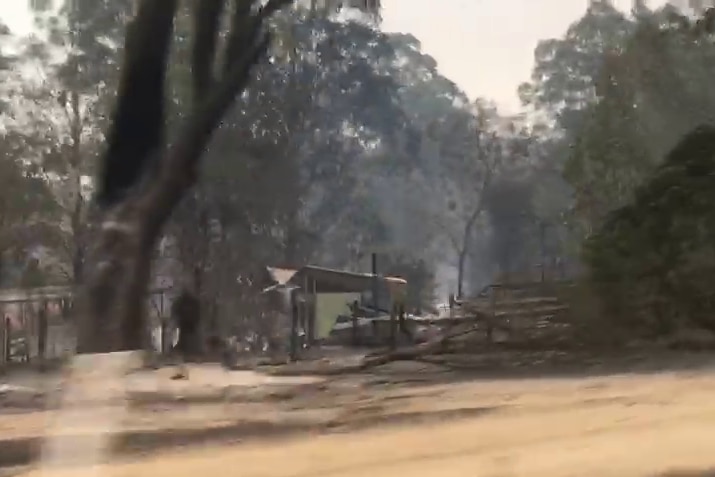 A still from a video showing dry farm land and a structure destroyed by fire.