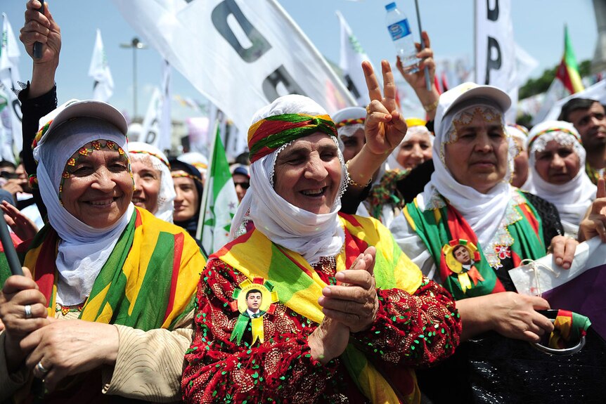 Kurdish women shout slogans and flash victory signs in Istanbul during an election rally